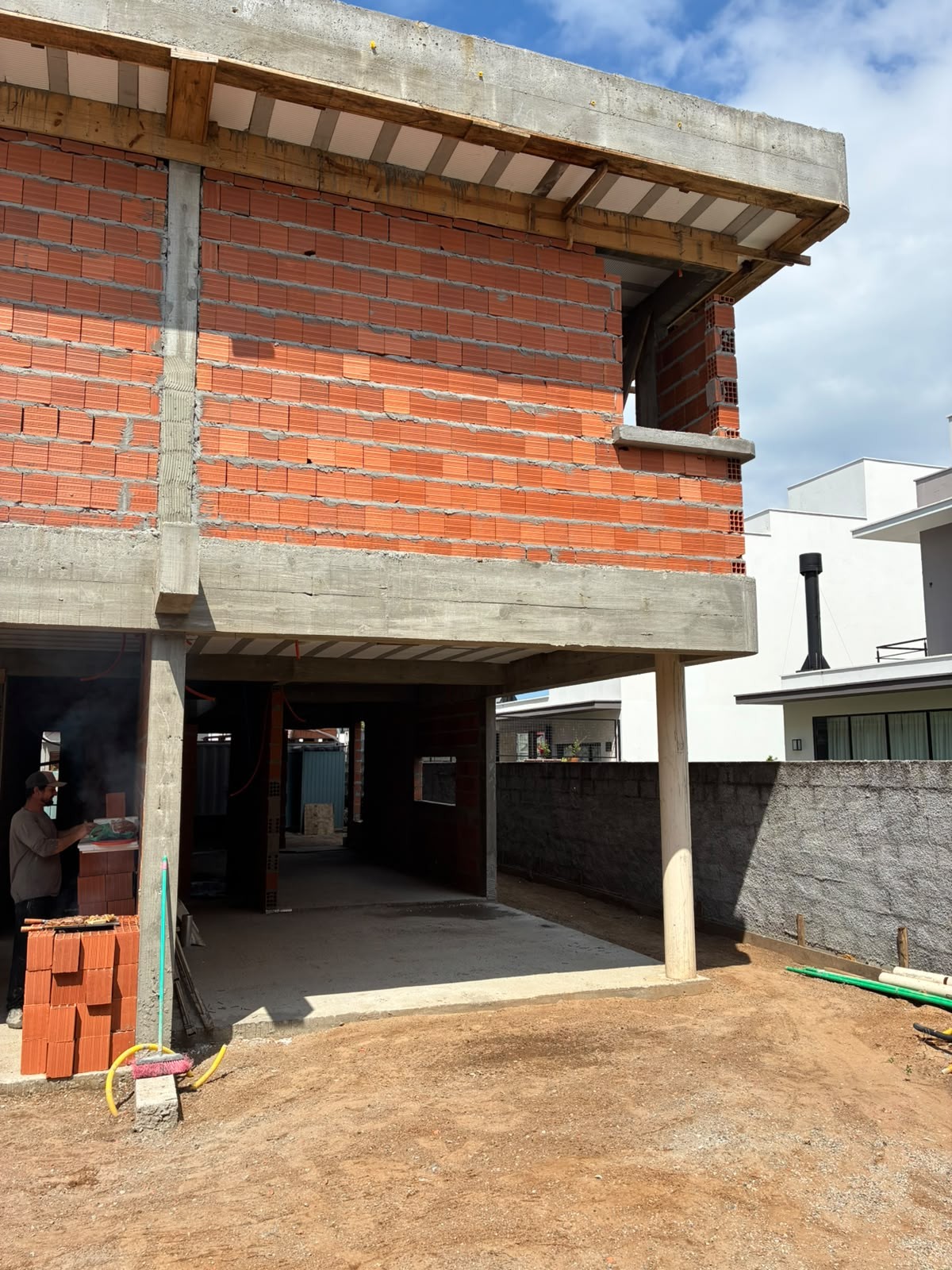 Obra em outubro de 2026 — vista lateral, com alvenaria em execução no pavimento superior